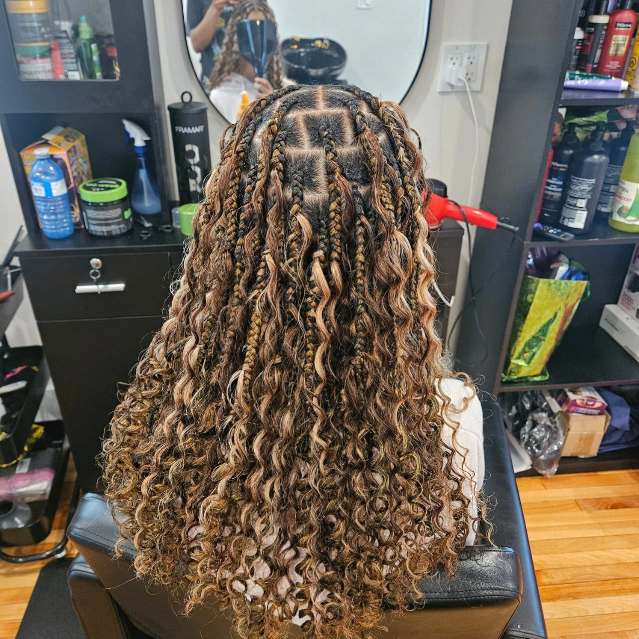 Long, textured boho braids with voluminous curls cascading down a client's back, a premium protective style by our textured hair care experts.