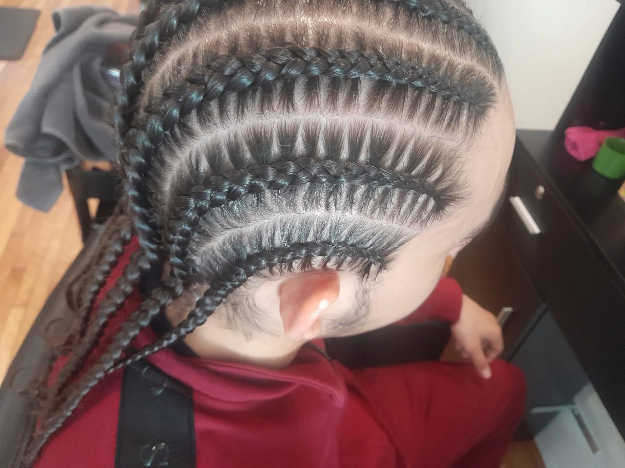 Side profile of a man with an intricate, curved cornrow design, highlighting expert tension-free braiding techniques for textured hair.