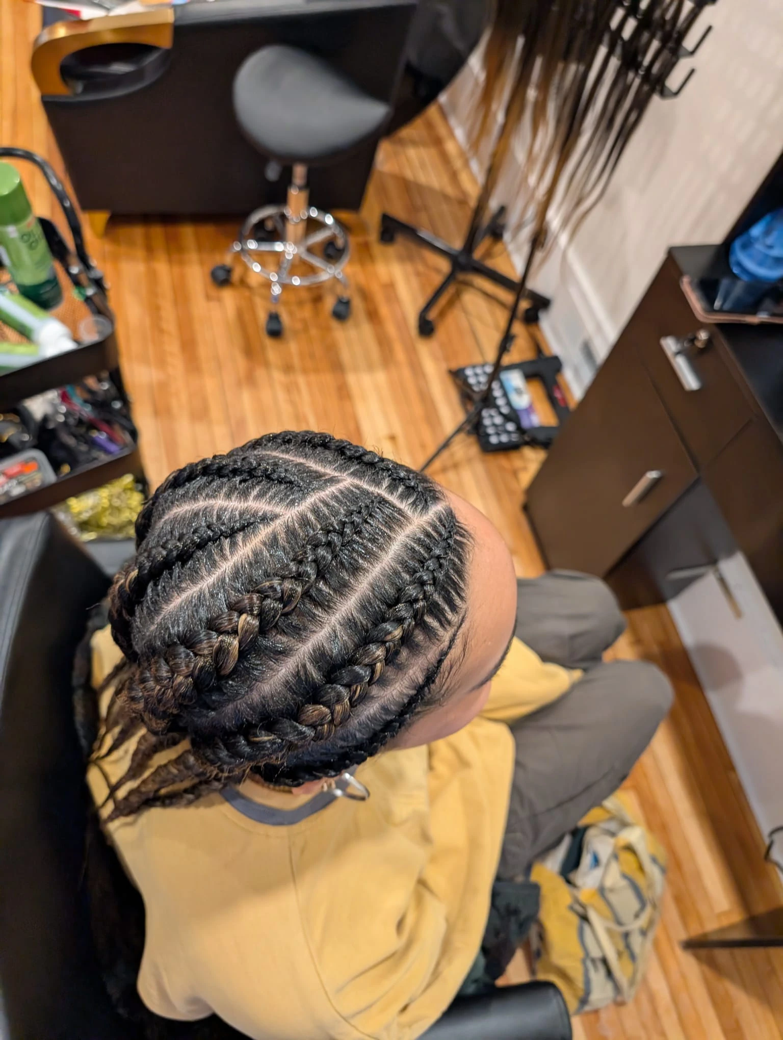 Top-down view of neat feed-in cornrows on a client, highlighting tension-free protective styling for textured hair.