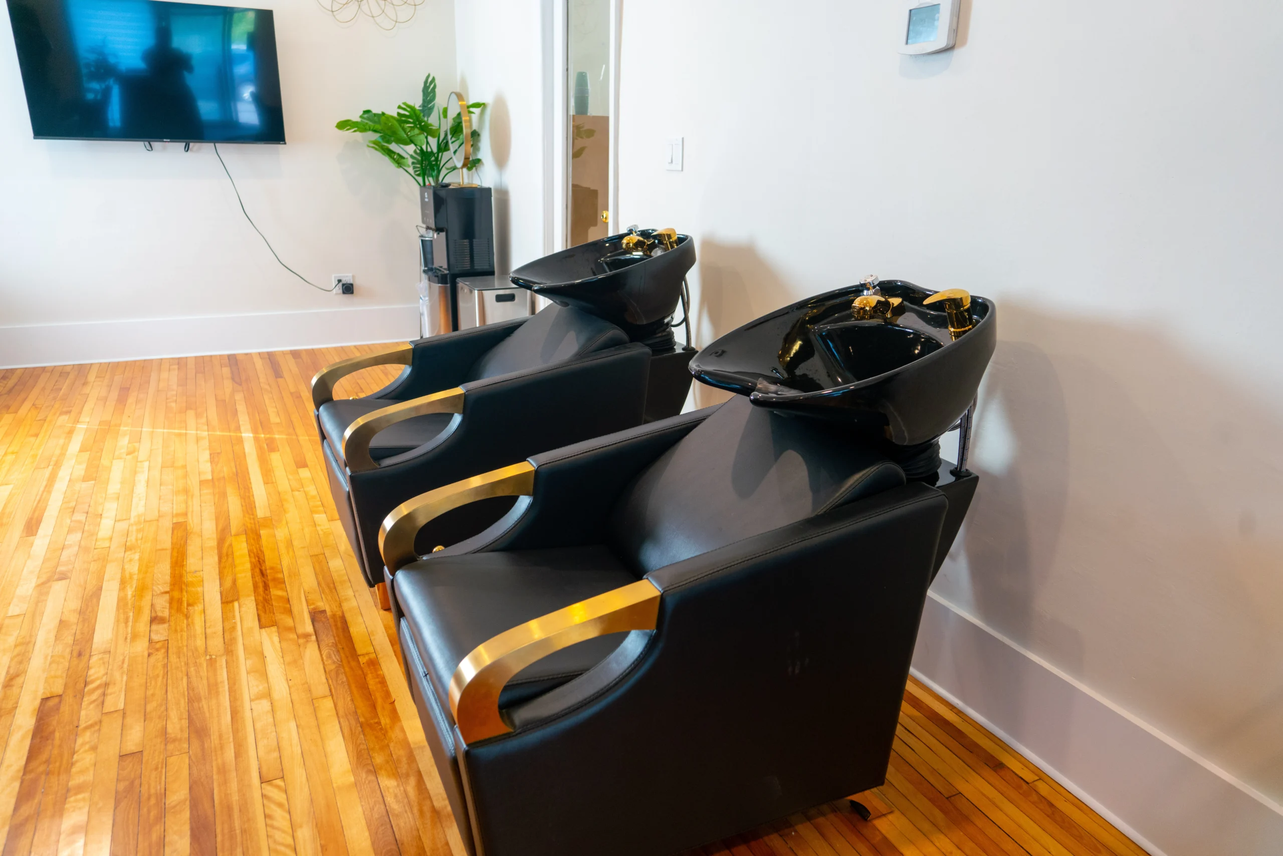 Dedicated hair washing area at our Kitchener salon, featuring two sleek black and gold wash basins designed for a relaxing, luxurious deep-conditioning experience.
