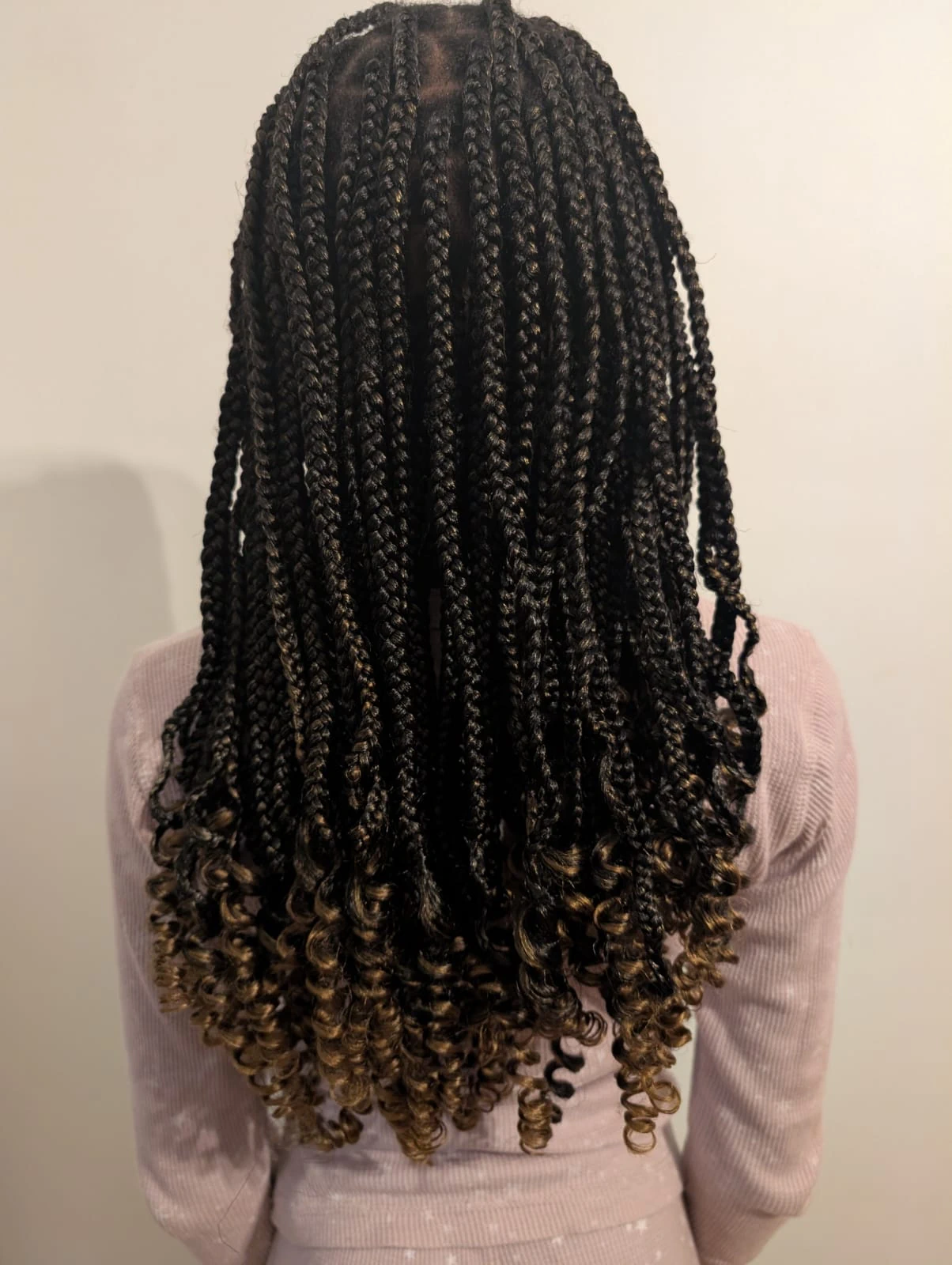 A child showcasing beautiful box braids with curly ends, a child-friendly protective style that prioritizes healthy hair.