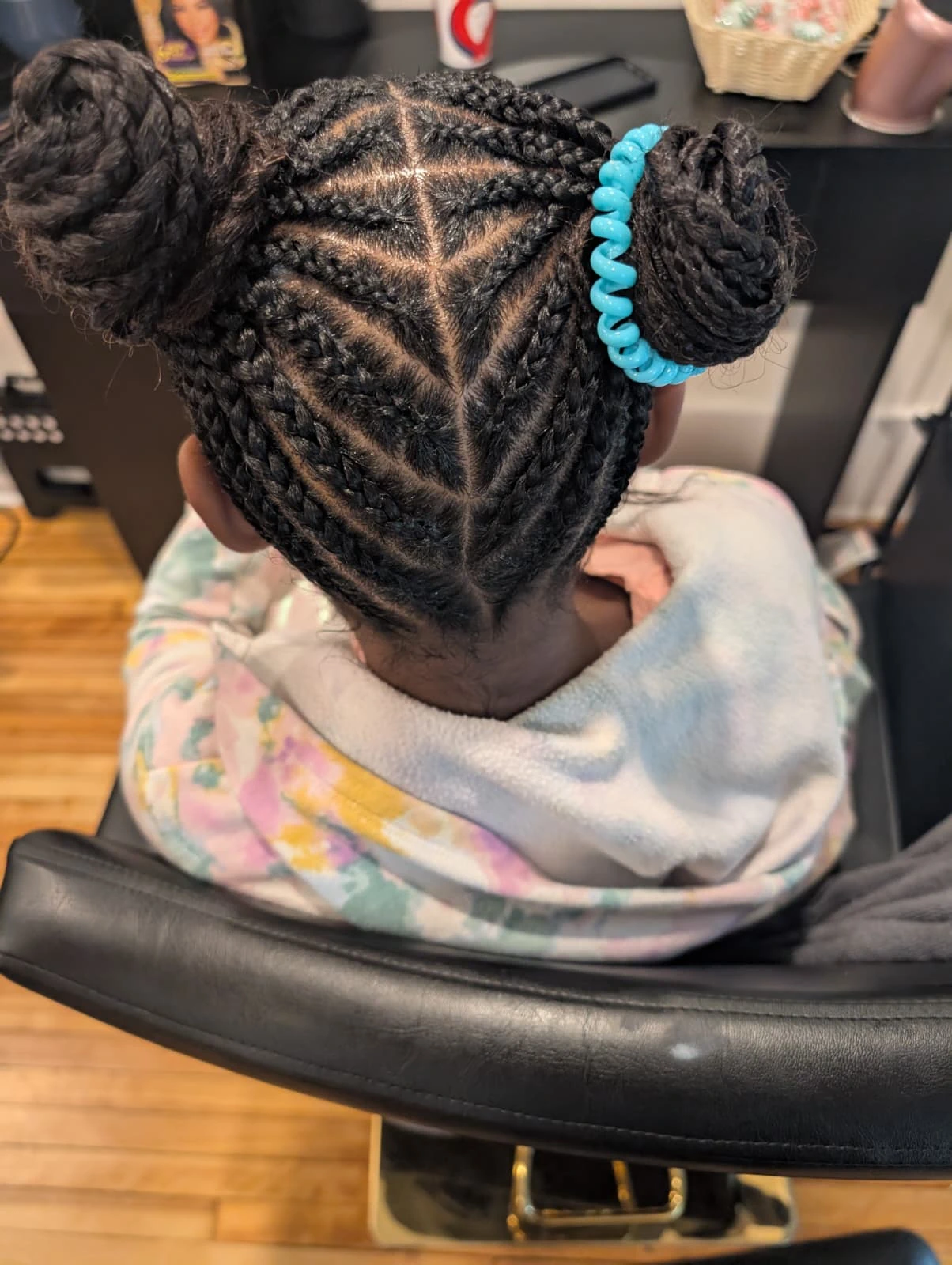 Overhead view of intricate cornrows styled into two neat braided buns on a child, highlighting our exceptionally gentle hair care.