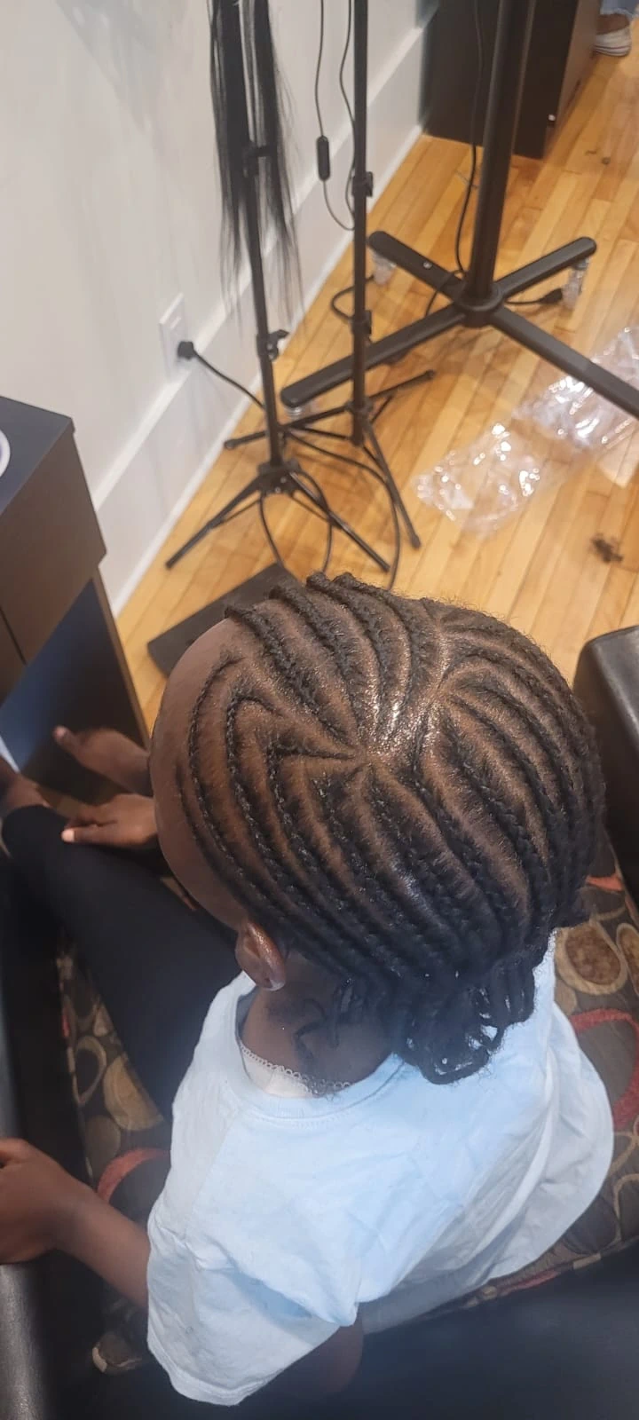Top-down look at an intricate curved cornrow design on a child, showcasing our specialized Afro hair care for little ones.