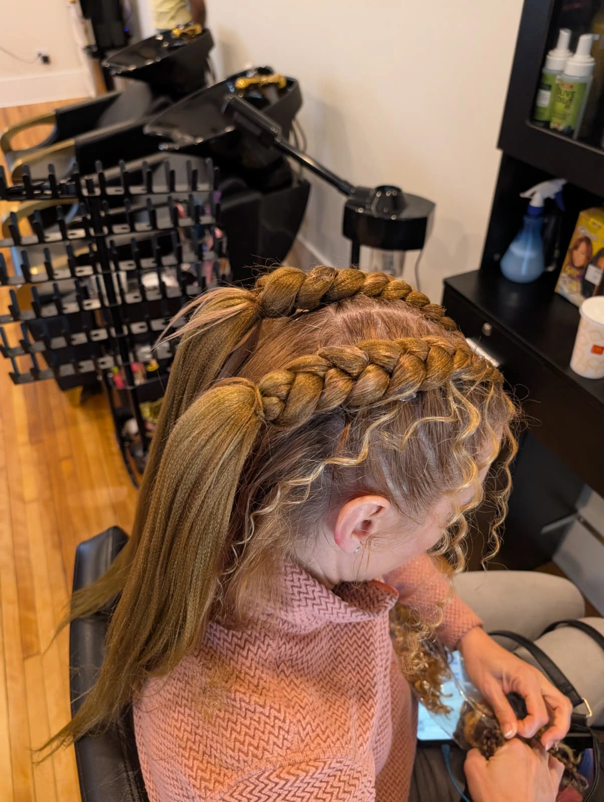 A stylist braiding two large half Dutch braids with extensions, providing a quick and stylish protective style for busy lifestyles.