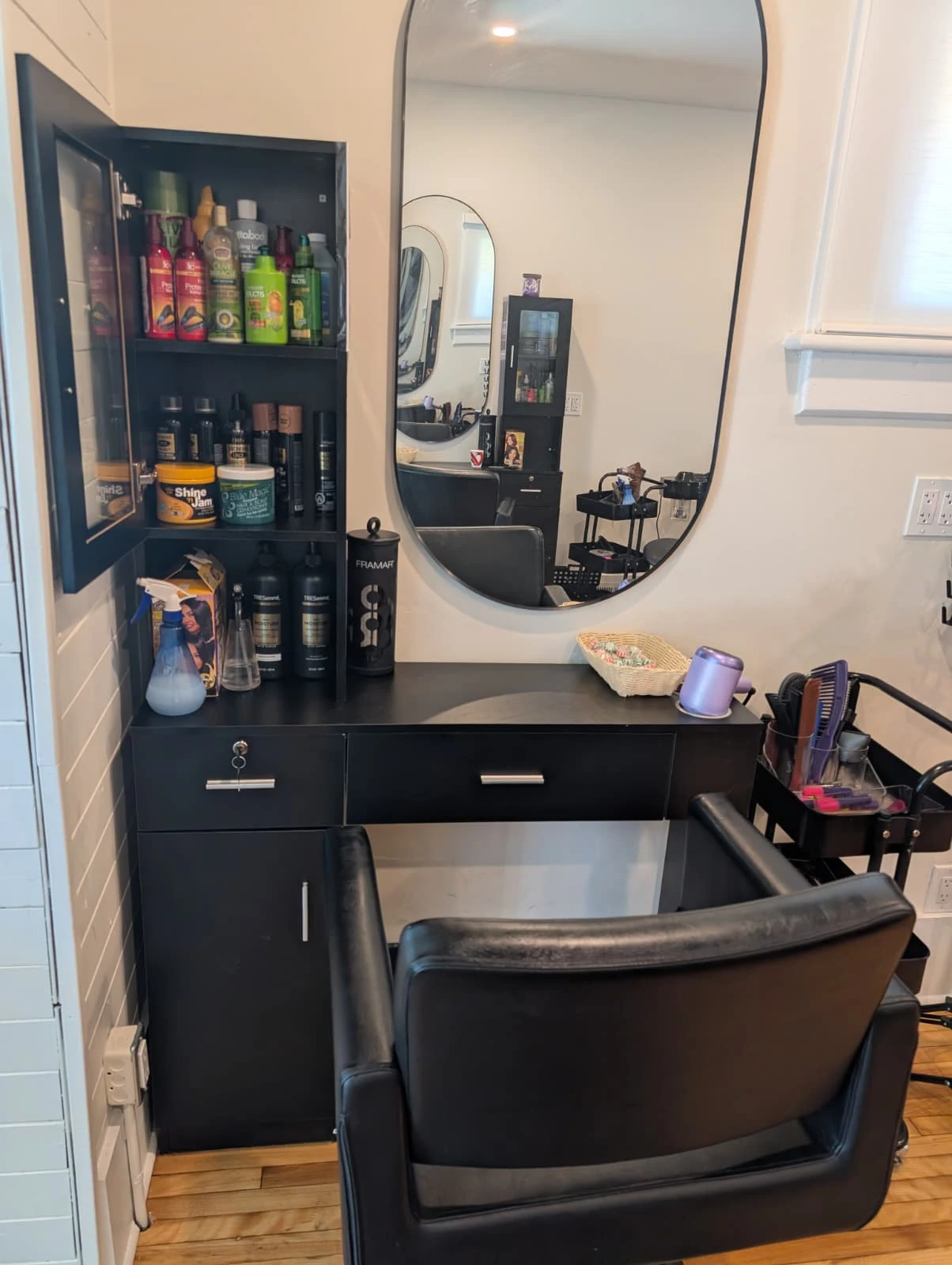 A modern, upscale styling station featuring a large oval mirror and premium hair care products at our Kitchener Afro-centric salon.