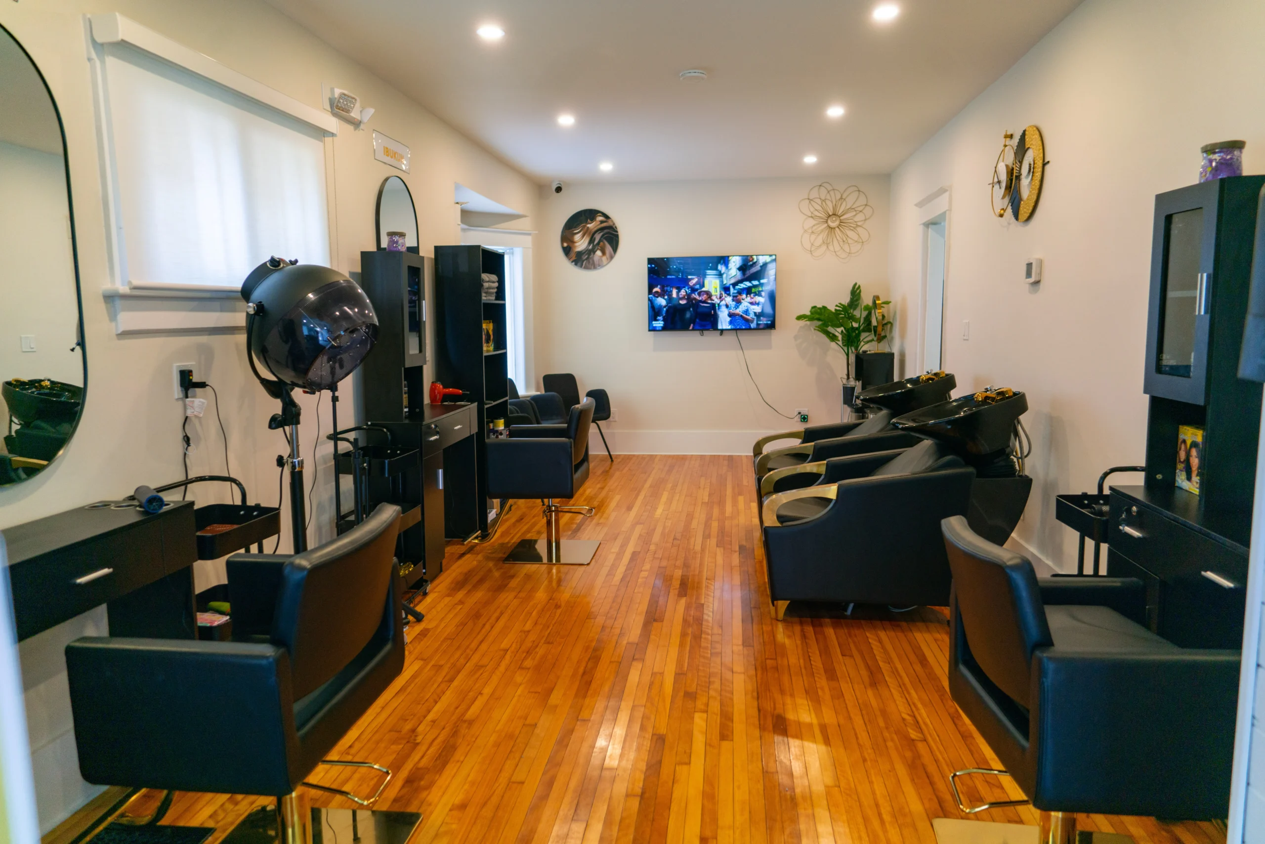 Spacious and bright styling area at Afro Royal Tresses, equipped with luxury black and gold salon chairs and hooded dryers for optimal natural hair care.